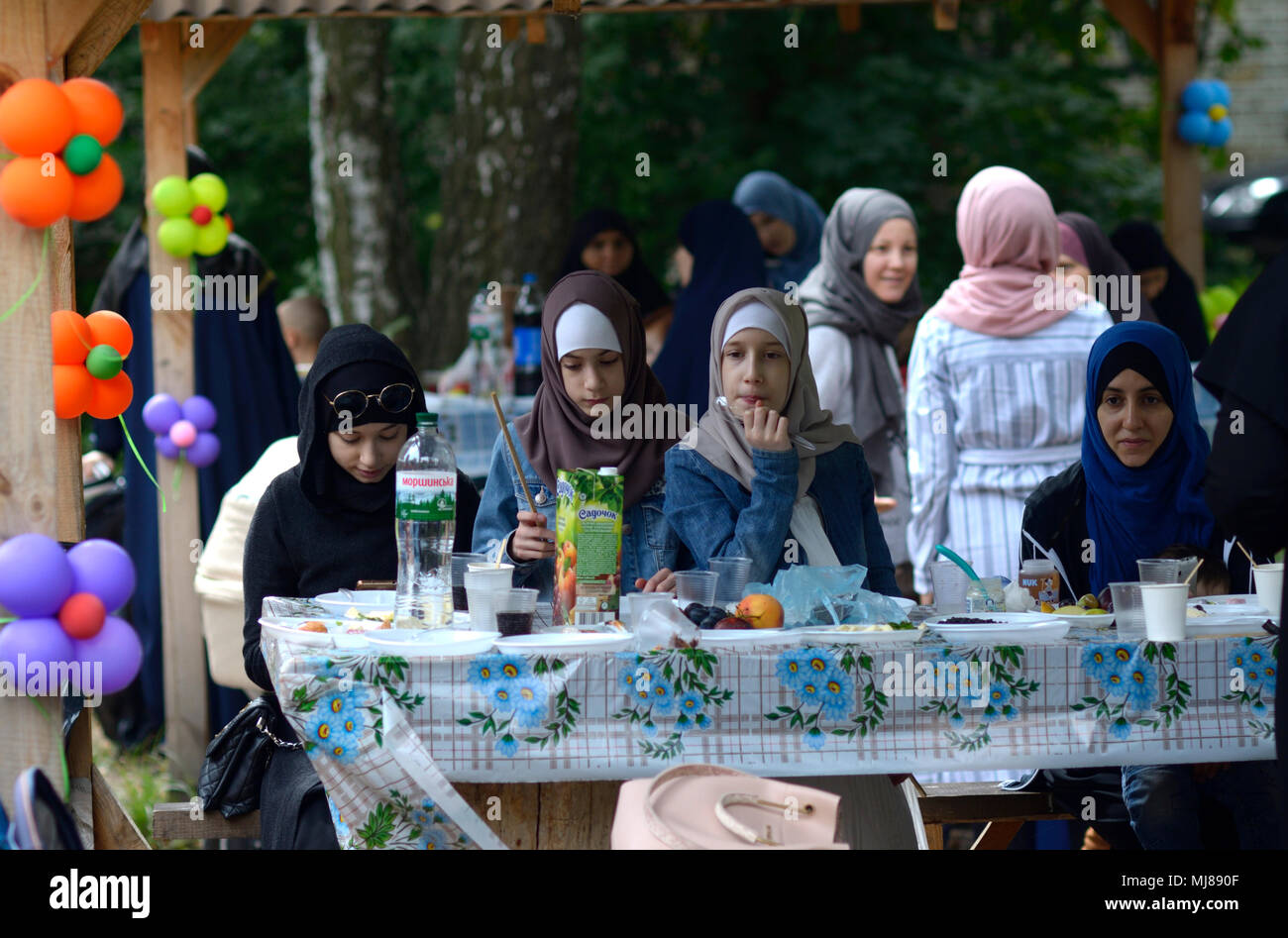 Muslim women in hijabs sitting at a table set with food. Celebration of Hidirellez (festival of arrival of spring).  Kiev, Ukraine Stock Photo