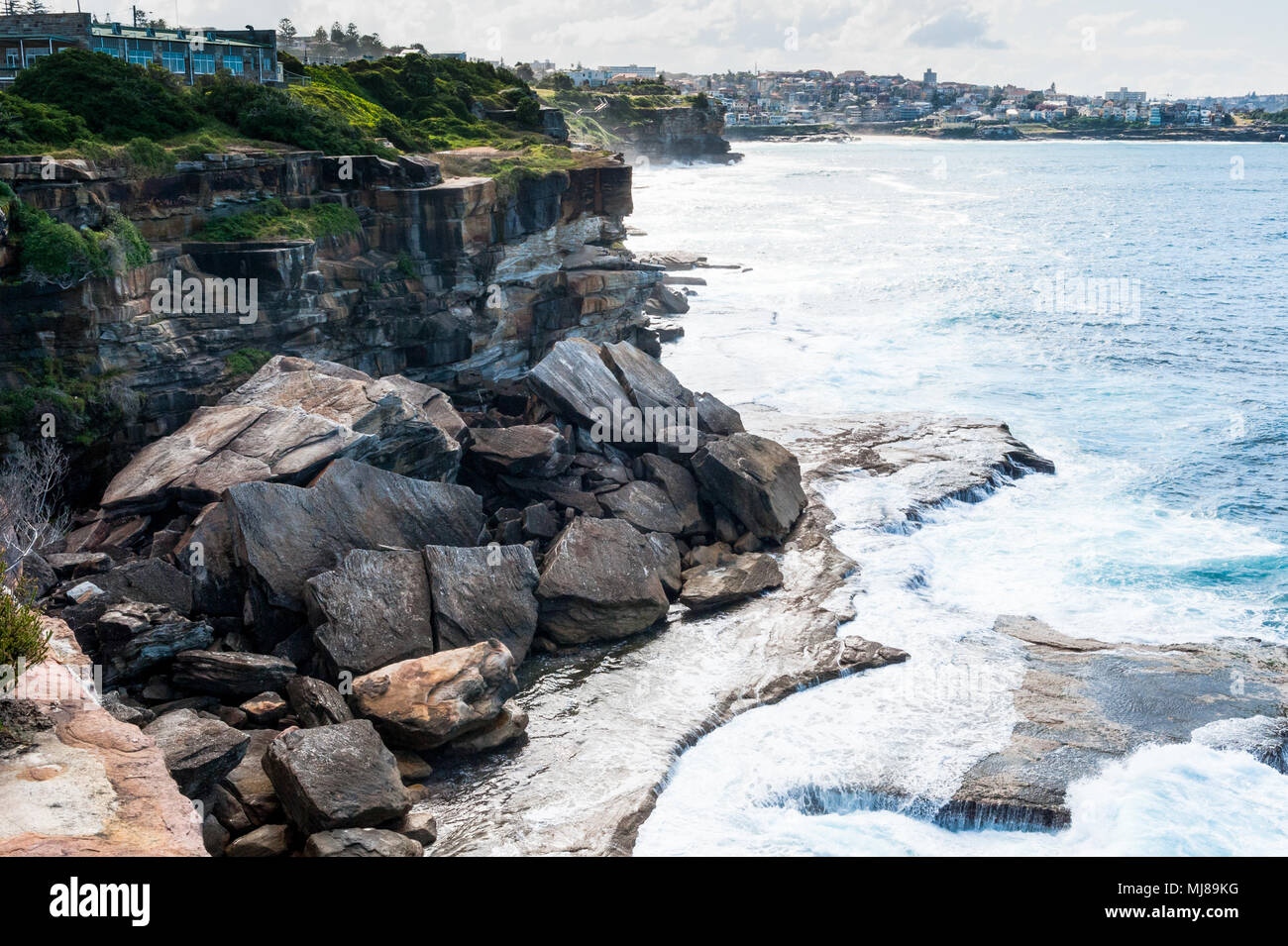 Massive rocks and boulders slip from the cliff into the sea as erosion impacts the shoreline of the famous Coogee Beach walk towards Bondi, Sydney. Stock Photo