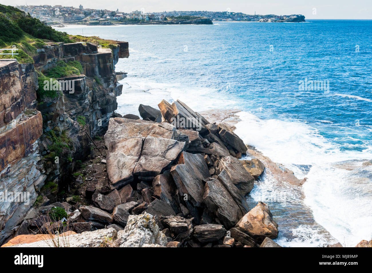 Massive rocks and boulders slip from the cliff into the sea as erosion impacts the shoreline of the famous Coogee Beach walk towards Bondi, Sydney. Stock Photo