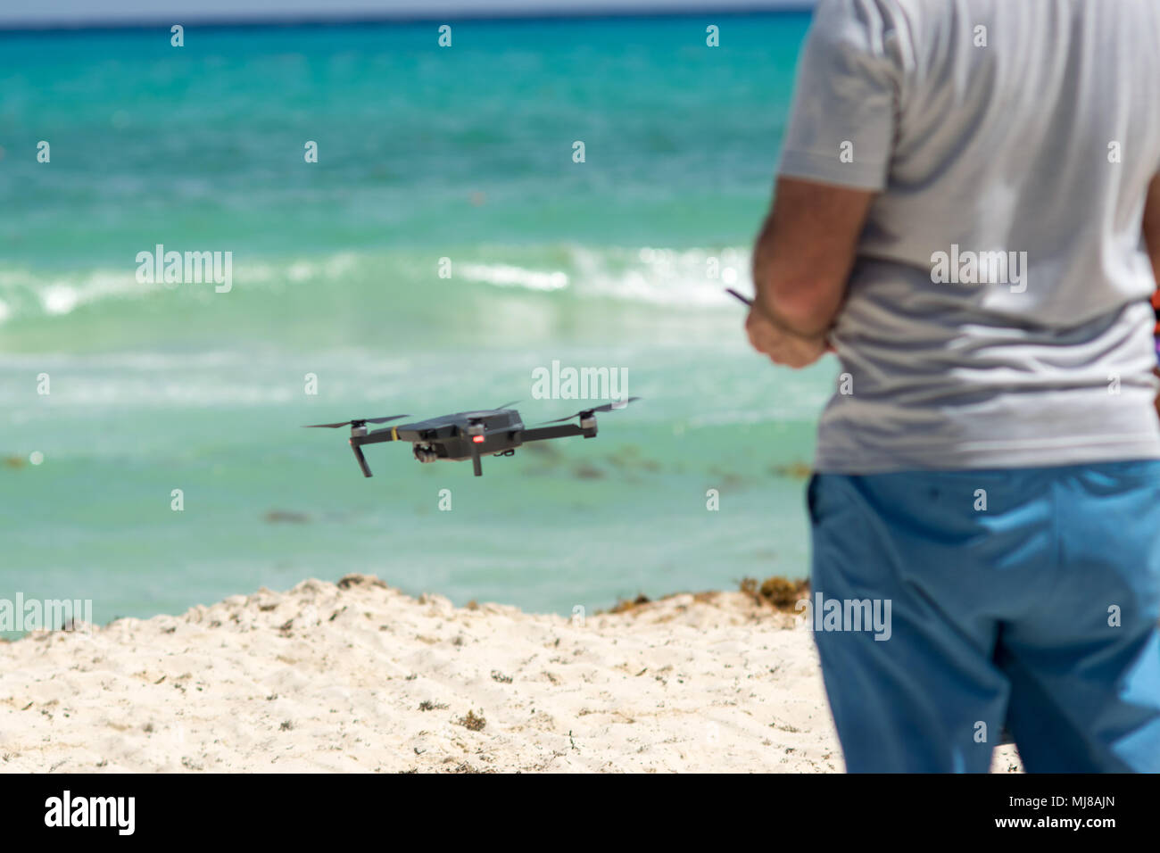 Man pilot controls the drone at beach Stock Photo