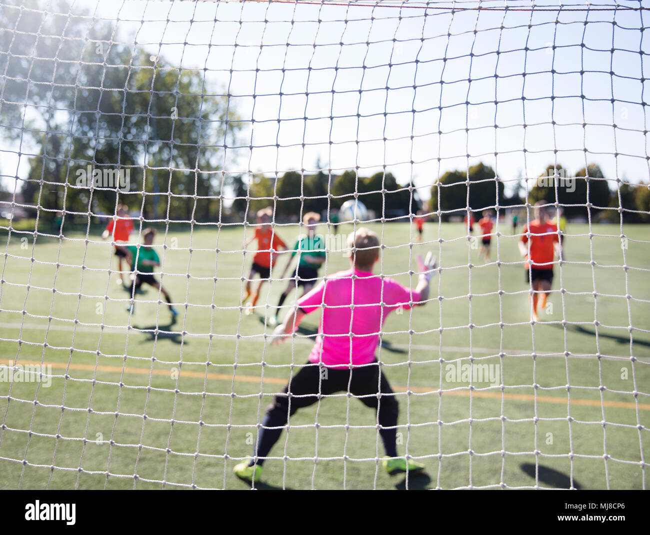 Group of men playing football on grass soccer field, seen from behind