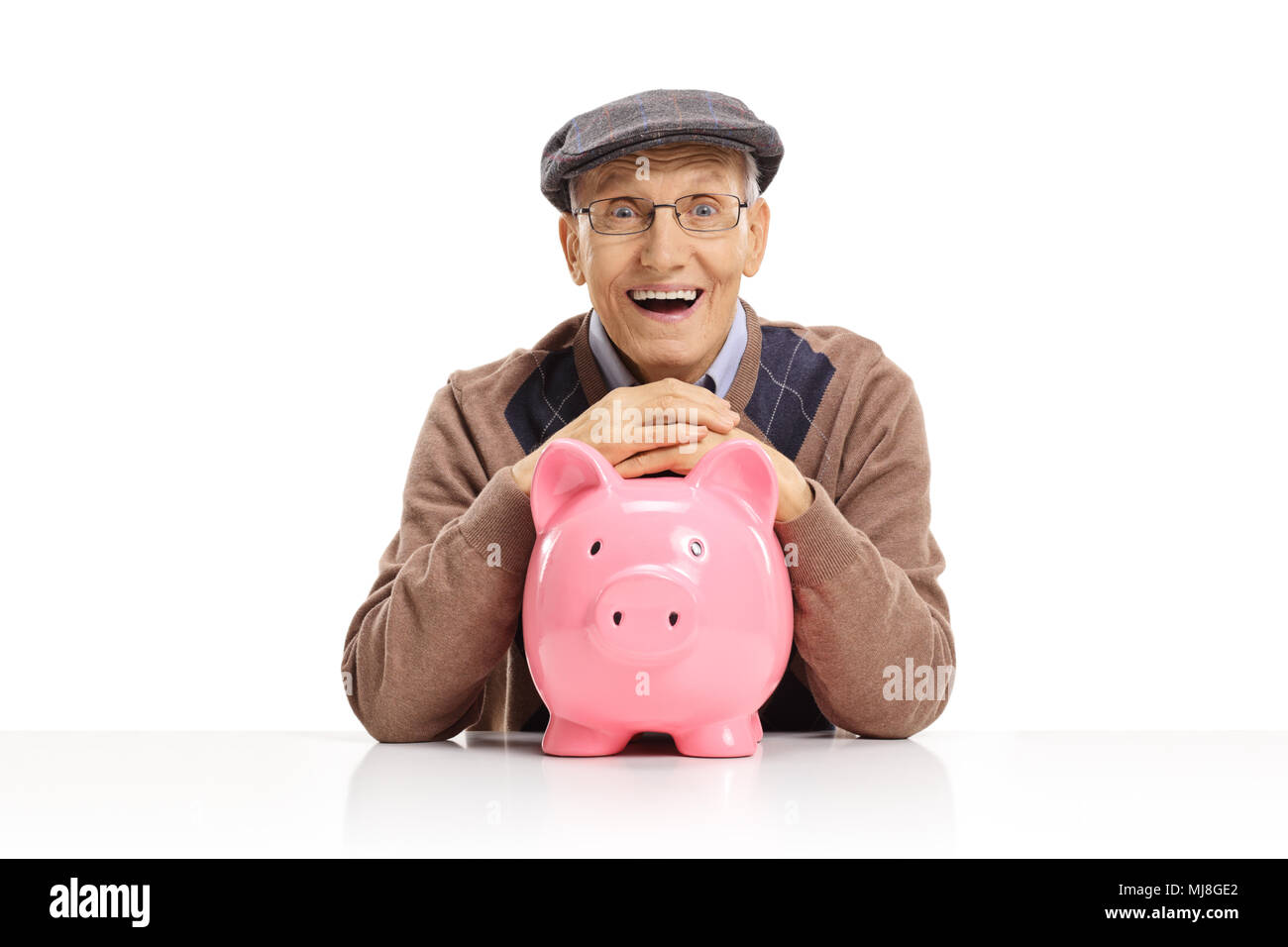 Happy senior with a piggybank sitting at a table isolated on white background Stock Photo
