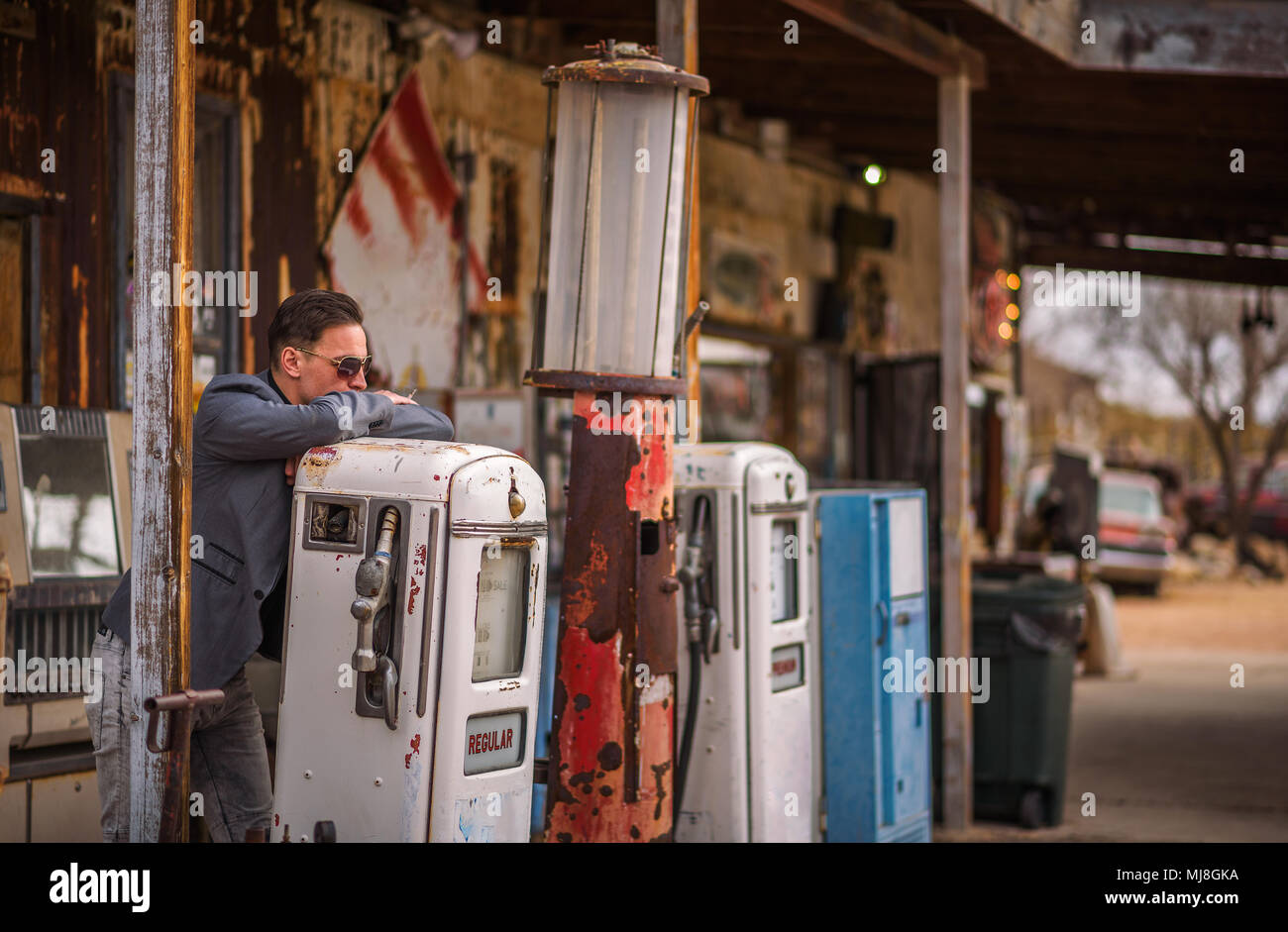 Young man smokes a cigarette at a vintage gas pump Stock Photo
