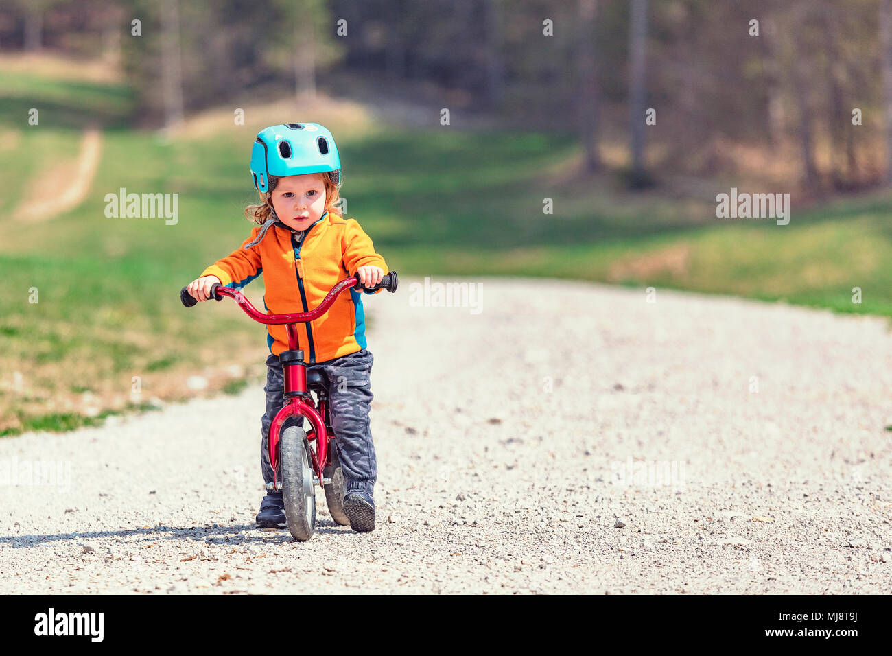 little confident kid training with her red bicycle on mountain road Stock Photo
