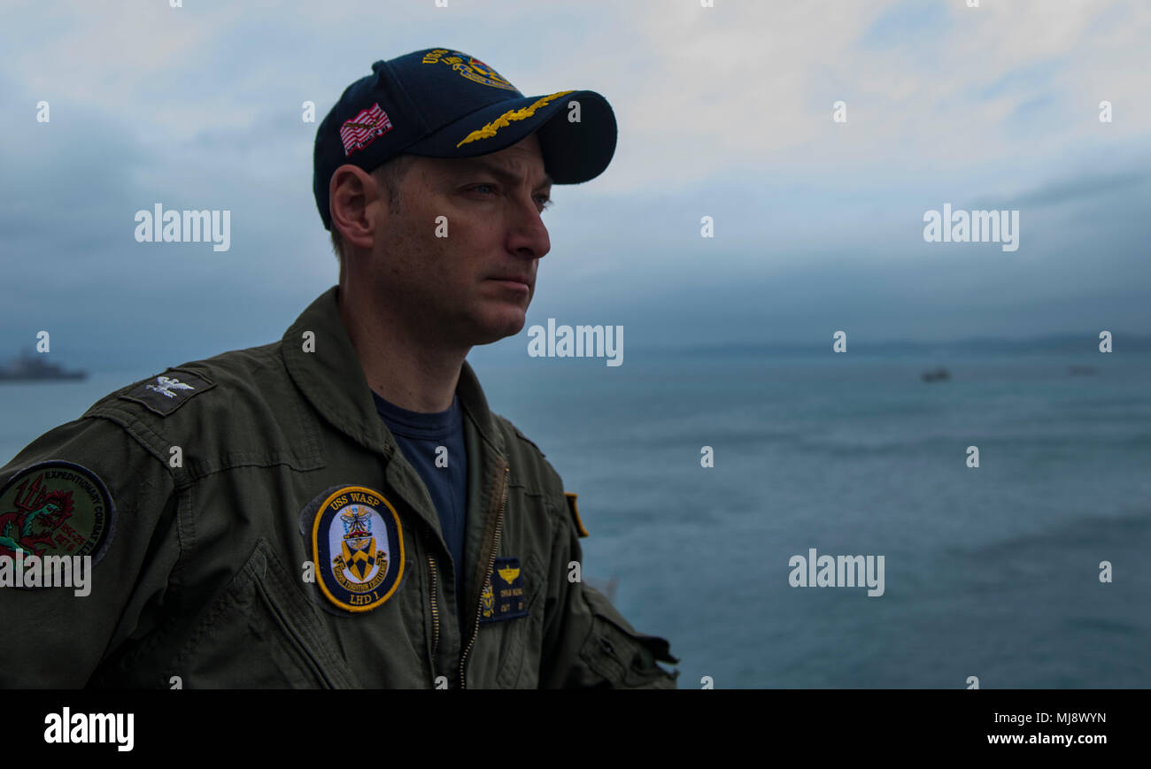 180421-N-BD308-0053 OKINAWA, Japan (April 21, 2018) Capt. Christopher Herr, executive ofﬁcer of the amphibious assault ship USS Wasp (LHD 1), observes the ship preparing to moor in Okinawa to disembark the 31st Marine Expeditionary Unit. Wasp, part of the Wasp Expeditionary Strike Group, has been operating with the MEU for nearly two months as part of a routine patrol in the Indo-Paciﬁc. (U.S. Navy photo by Mass Communication Specialist 3rd Class Levingston Lewis/Released) Stock Photo
