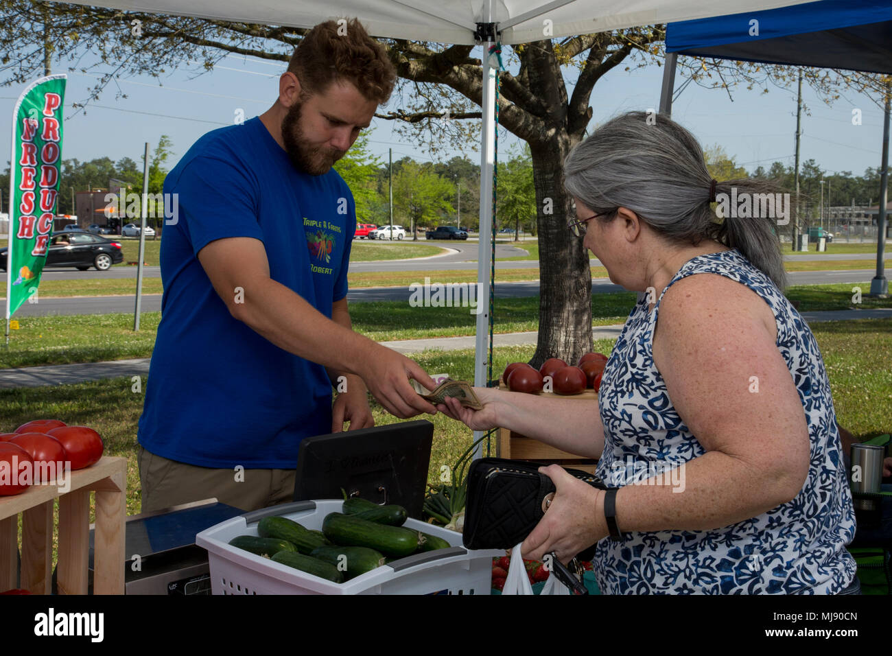 Robert. R. Roberts Jr., left, farmer, Triple R Farms, sells local produce during the Onslow County Farmers' Market fifth annual Seasonal Opening at the Harriotte B. Smith Library on Marine Corps Base Camp Lejeune, N.C., April 19, 2018.  The Onslow County Farmers' Market provides locally grown produce and handmade artisan products to customers. (U.S. Marine Corps photo by Sgt. Judith L. Harter) Stock Photo