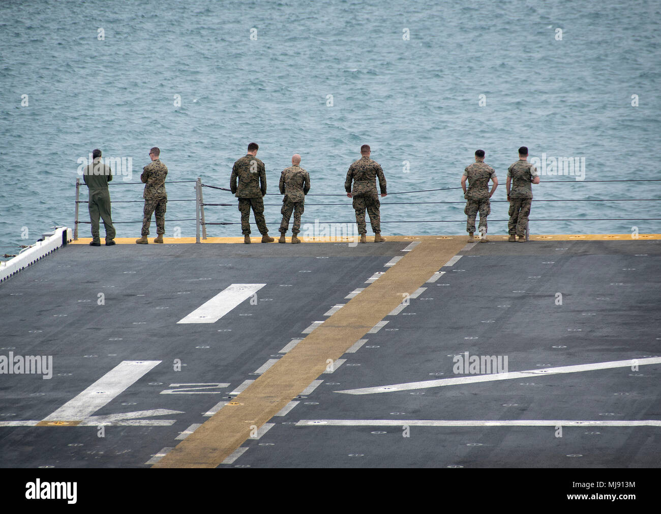180421-N-RI884-0274 PHILIPPINE SEA (April 21, 2018) Marines aboard the amphibious assault ship USS Wasp (LHD 1) observe the ship pulling into Okinawa to disembark the 31st Marine Expeditionary Unit. Wasp, part of the Wasp Expeditionary Strike Group, has been operating with the MEU for nearly two months as part of a routine patrol in the Indo-Pacific. (U.S. Navy photo by Mass Communication Specialist 1st Class Daniel Barker/Released) Stock Photo