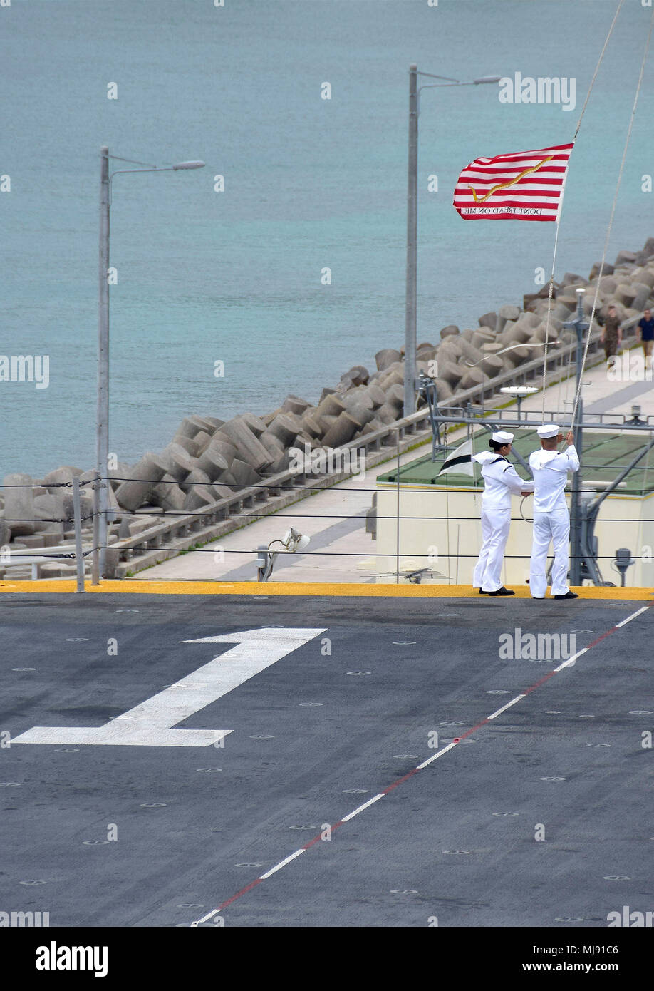 180421-N-RI884-0322 PHILIPPINE SEA (April 21, 2018) Sailors aboard the amphibious assault ship USS Wasp (LHD 1) moor ship's colors as the ship arrives in Okinawa to disembark the 31st Marine Expeditionary Unit. Wasp, part of the Wasp Expeditionary Strike Group, has been operating with the MEU for nearly two months as part of a routine patrol in the Indo-Pacific. (U.S. Navy photo by Mass Communication Specialist 1st Class Daniel Barker/Released) Stock Photo