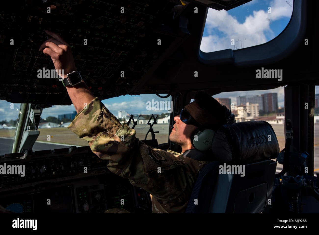 U.S. Air Force Maj. Geno Salazar both 21st Airlift Squadron C-17 Globemaster III pilots, makes post flight adjustments after landing with Denton Program emergency response vehicles to La Aurora International Airport, Guatemala City, Guatemala, April 20, 2018. The Denton Program is a Department of Defense transportation program that moves humanitarian cargo, donated by U.S. based Non-Governmental Organizations to developing nations to ease human suffering. The emergency vehicles were donated by the Mission of Love Foundation, they are the largest user of the Denton Program, having delivered med Stock Photo