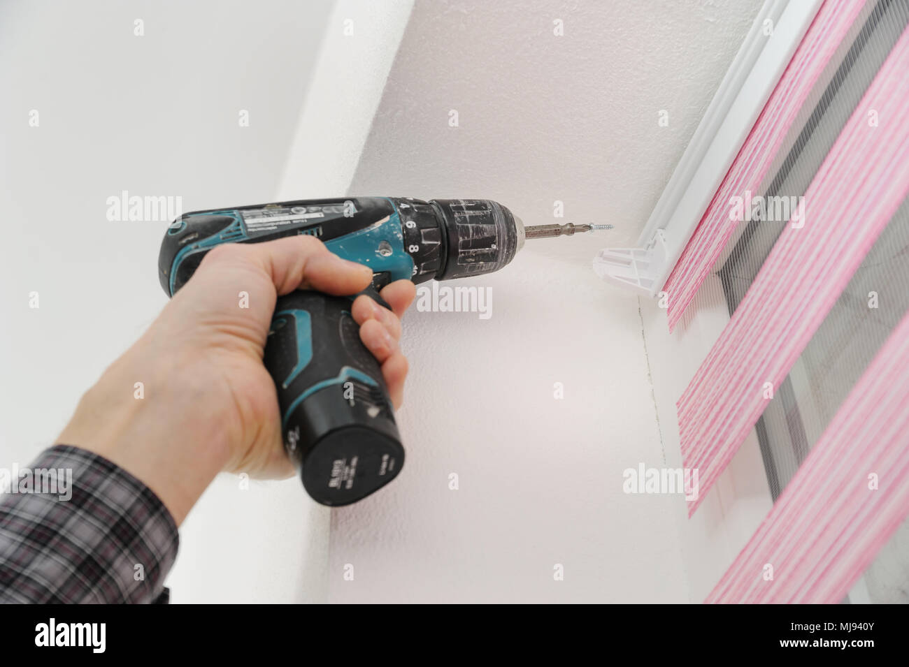 Installing fabric roller blinds. A man fixes basis blinds to frame the window. Stock Photo