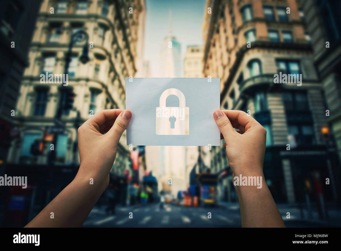 Woman hands holding a paper sheet with lock symbol in the middle of the street in a big city. Padlock as security symbol in business. Data privacy pro Stock Photo