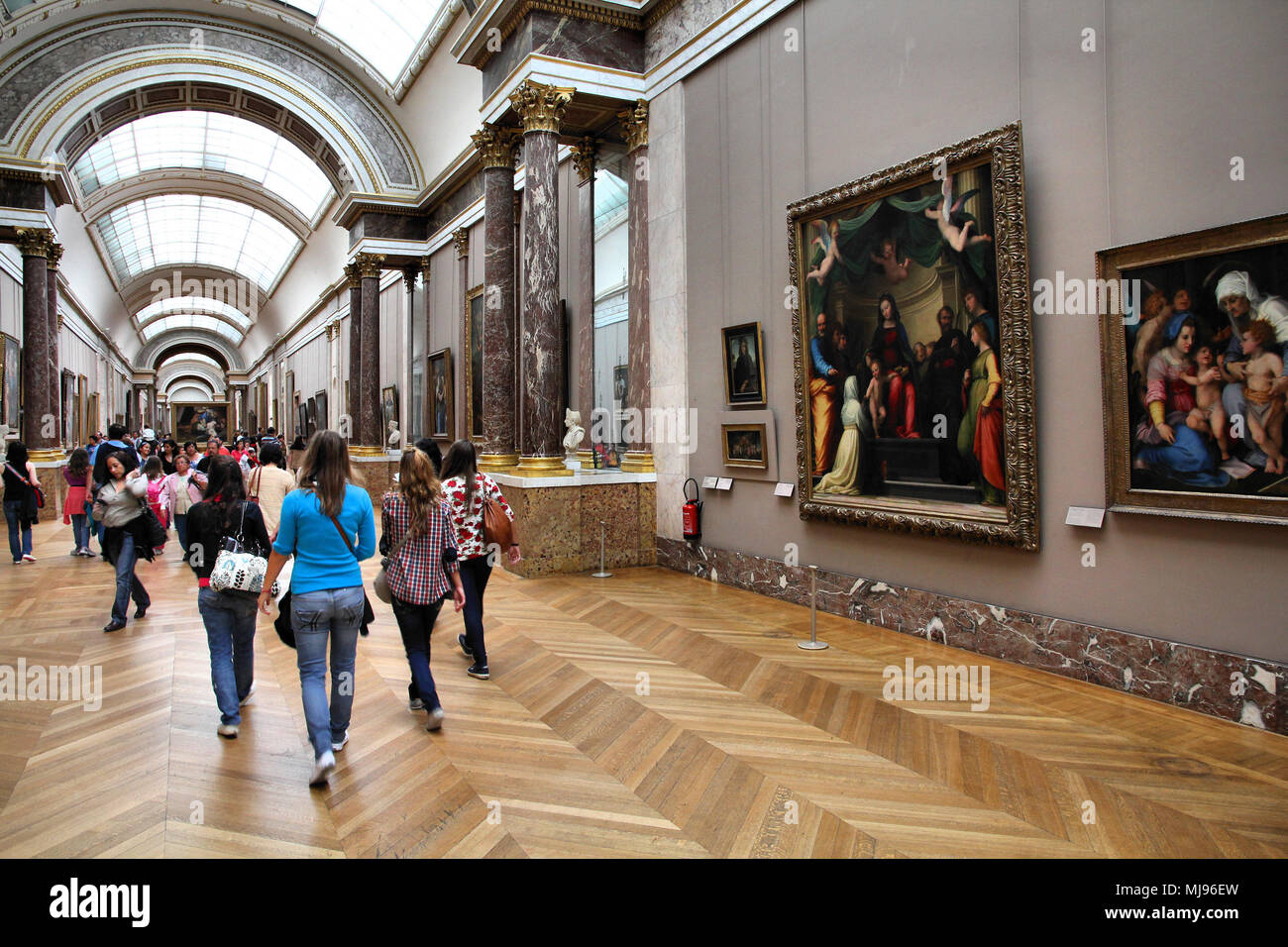 PARIS - JULY 22: Visitors admire paintings on July 22, 2011 in Louvre Museum, Paris, France. With 8.5m annual visitors, Louvre is consistently the mos Stock Photo
