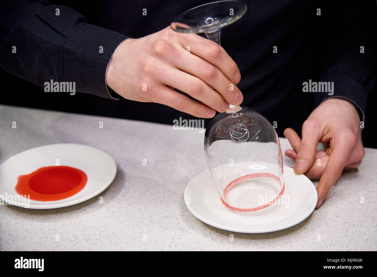 Inverted glass of the barman is lowered into a plate with sugar crumbs Stock Photo