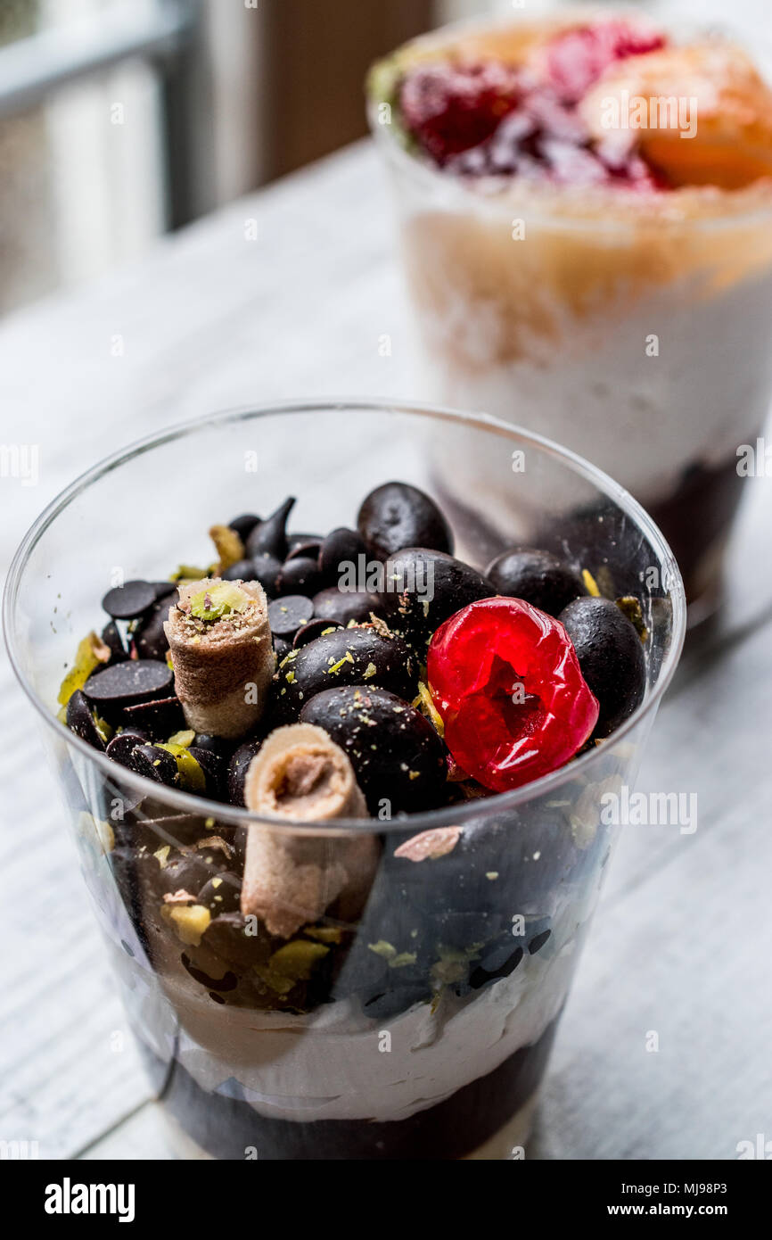 Chocolate Morsels and mixed fruit Parfait with yogurt in glass cup on white wooden surface Stock Photo