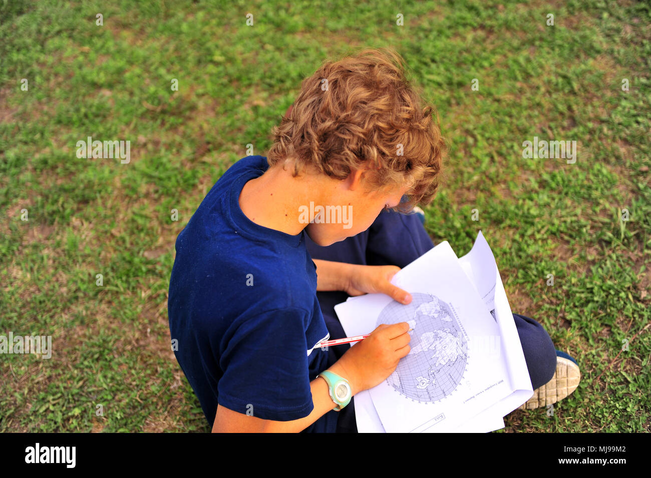 Boy studies geography sitting on grass outdoors Stock Photo - Alamy