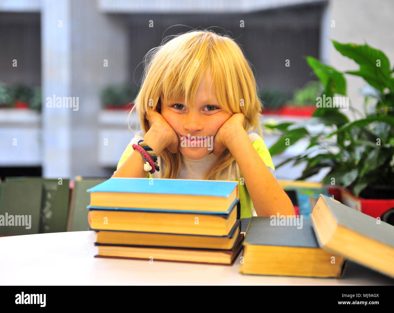 Boy with books sitting in library Stock Photo - Alamy