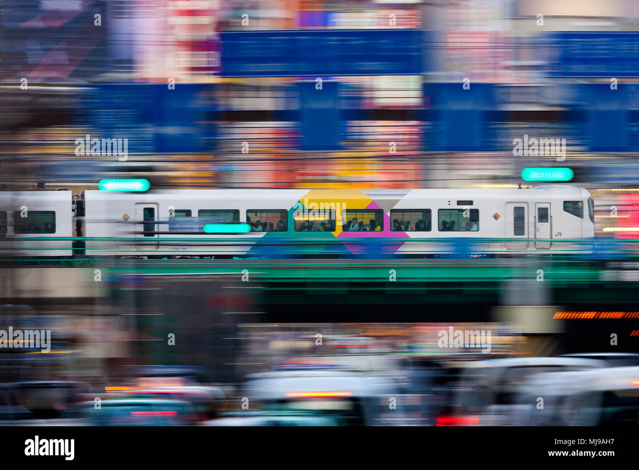 Japanese Commuter Train running over a bridge in Tokyo's Shinjuku district. Panned shot with blurred fore- and background. Stock Photo