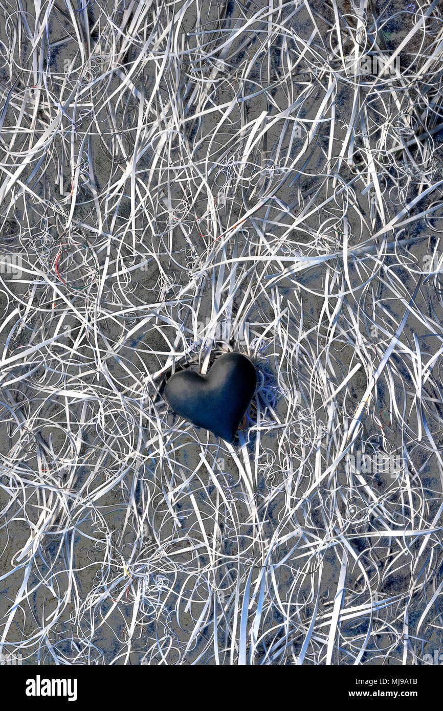 A dark heart at the centre of a tangle of card offcuts on a background of slate. Stock Photo