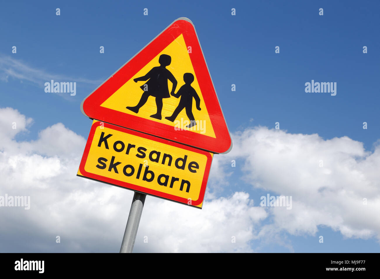 Swedish road sign, warning for children with additional sign with the text, intersecting school children, isolate on blue sky with clouds. Stock Photo