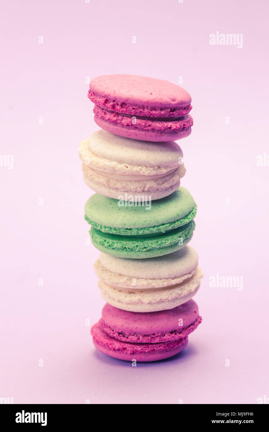 Sweet and colourful french macaroons or macaron on light purple background, Dessert. Stock Photo