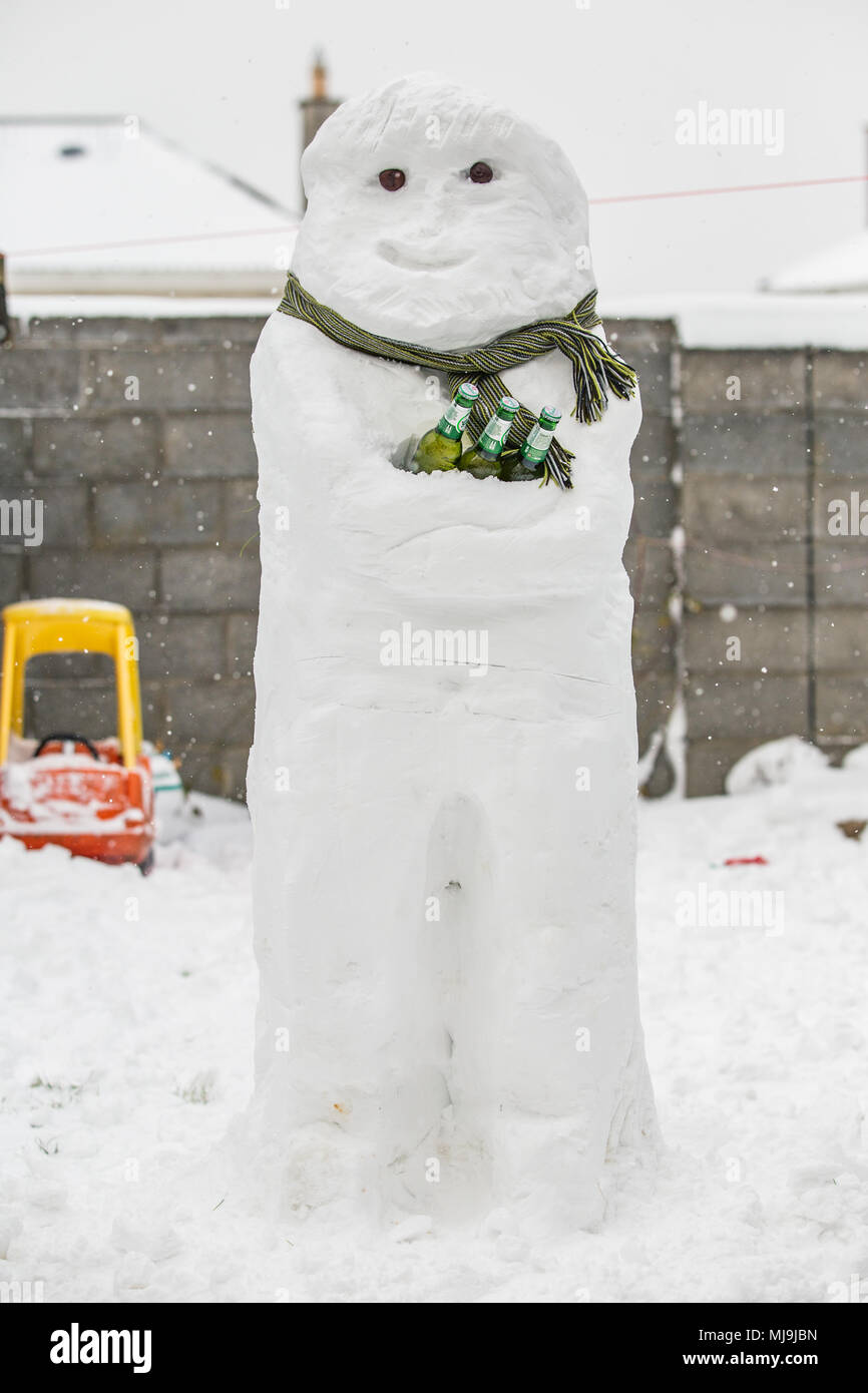 Snowman with a scarf holding bottles of Heineken beer Stock Photo