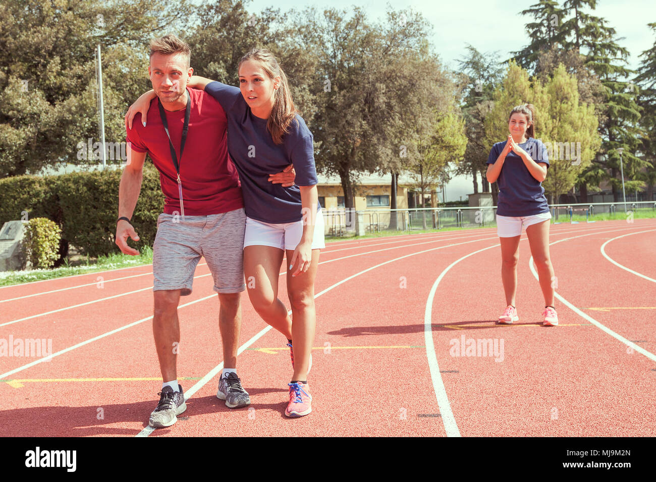 young athlete injured to knee on the track while being helped by his