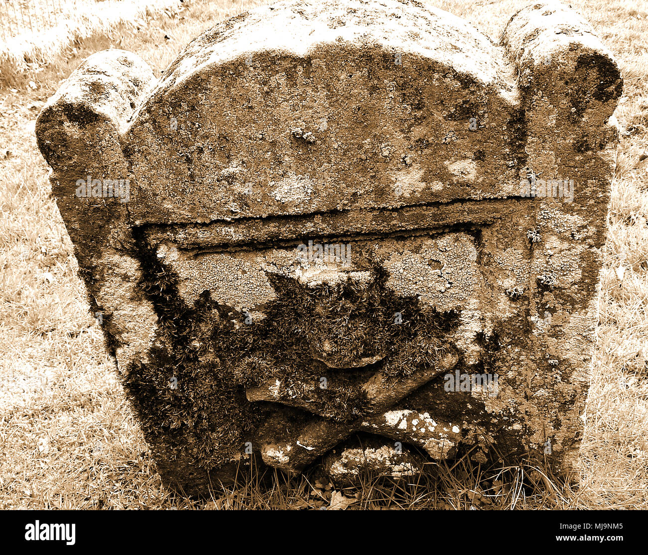 Ancient skull and crossbow symbolism on gravestones in a Dumfries and Galloway, Scotland, country graveyard. (Memento Mori)mortality Stock Photo