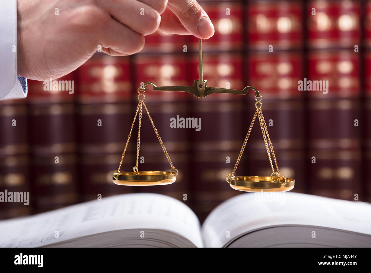 Judge Holding Justice Scale In Front Of Law Book Stock Photo