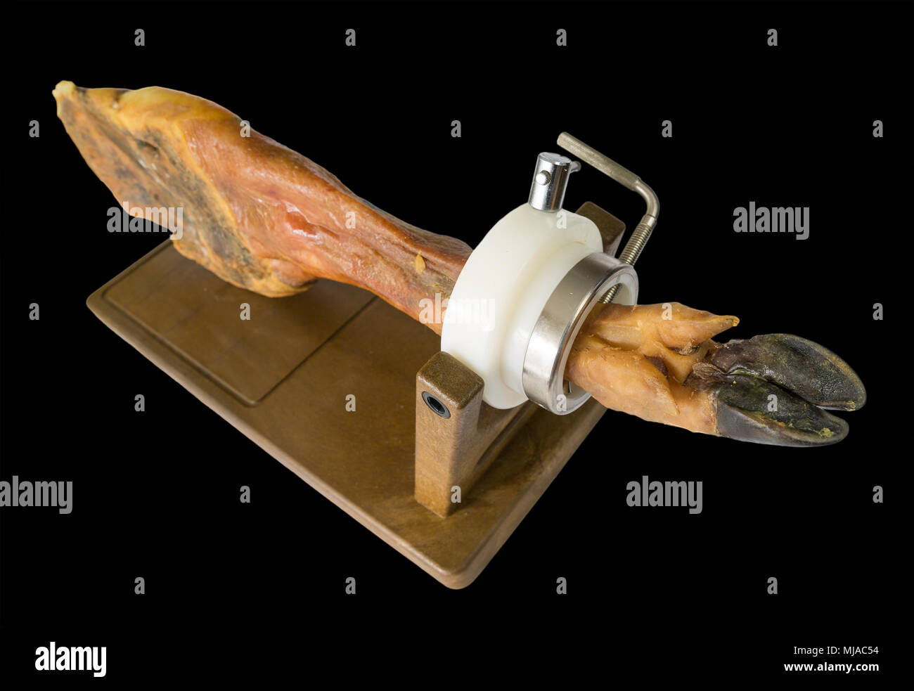 Edge view of whole serrano ham leg over wood, black background Stock