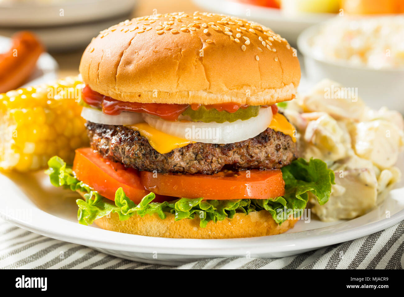 Memorial Day Backyard Babecue Meal with Hamburgers Hot dogs Salads and Chips Stock Photo