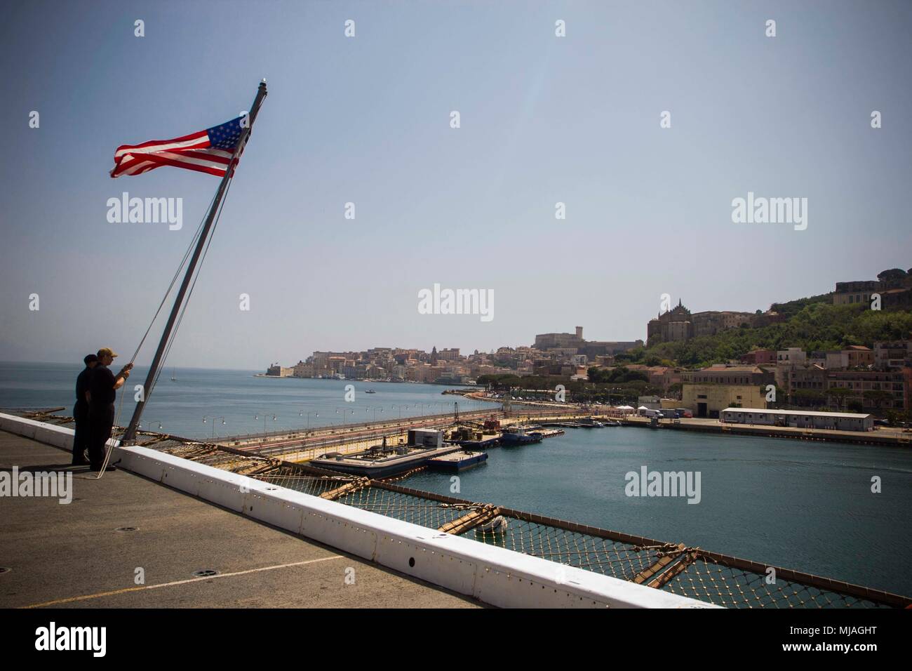 GAETA, Italy (April 25, 2018)  U.S. Navy Sailors lower the American flag aboard the San Antonio-class amphibious transport dock USS New York (LPD 21) as the ship departs Gaeta, Italy, April 25, 2018. The port stop was an opportunity to enhance U.S.-Italy relations as the two nations work together for a stable, secure and prosperous Europe. U.S. 6th Fleet, headquartered in Naples, Italy, conducts the full spectrum of joint and naval operations, often in concert with allied and interagency partners, in order to advance U.S. national interests and security and stability in Europe and Africa. (U.S Stock Photo
