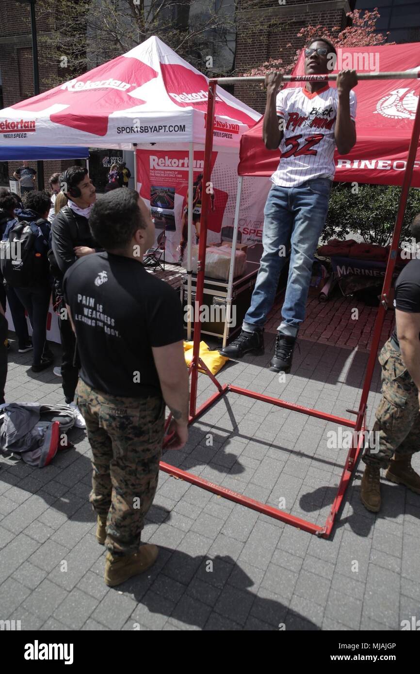 PHILADELPHIA – 17-year-old Shyyon Frazier, a student athlete for Seneca Valley High School in Germantown, Maryland, participates in a Marine Corps pull-up challenge during the Penn Relays at Franklin Field at the University of Pennsylvania campus in Philadelphia, April 26, 2018. Marines partnered with and attended the 124th Penn Relays to foster positive relationships with student athletes and coaches and to educate the track and field community on opportunities within the Marine Corps. (U.S. Marine Corps photo by LCpl. Naomi Marcom) Stock Photo