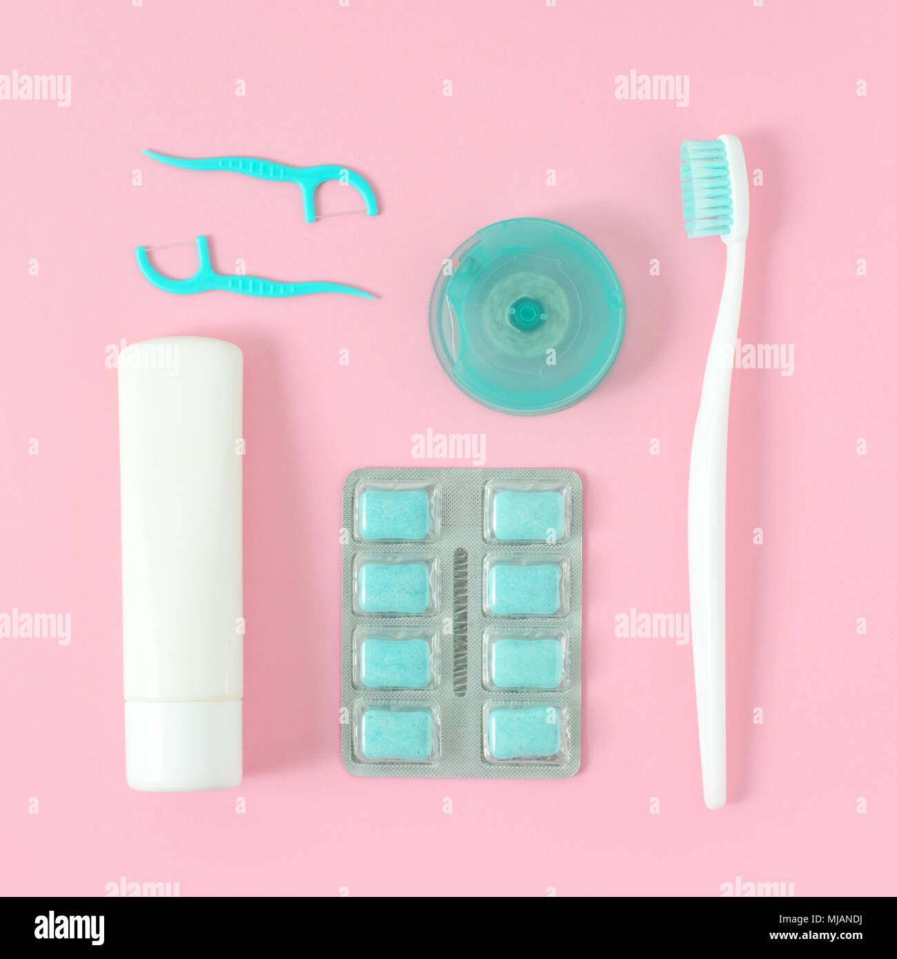 Toothbrushes, toothpaste, and chewing gum set on pink background