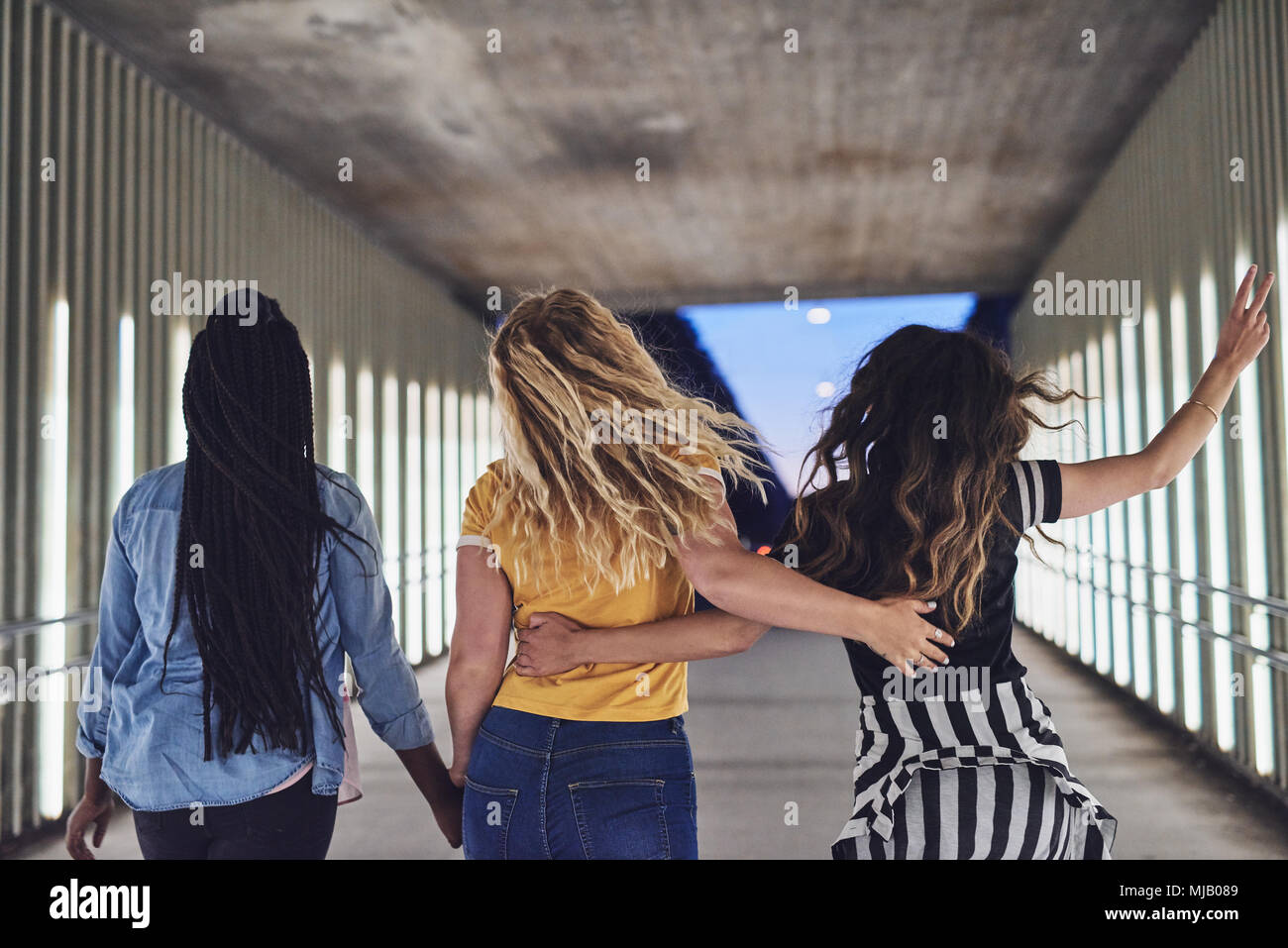 Rearview Of A Group Of Diverse Young Female Friends Walking Arm In Arm Together Down A Walkway In The City At Night Stock Photo Alamy