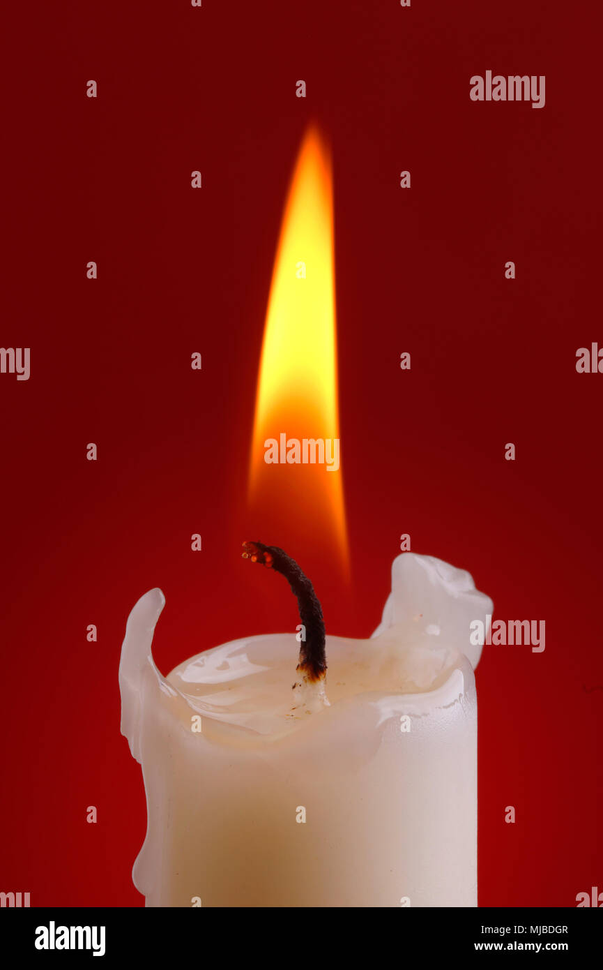 Close up of a candle ligt on red background. Stock Photo