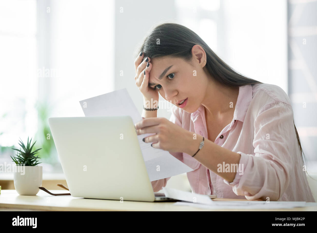 Worried frustrated woman shocked by bad news while reading lette Stock Photo