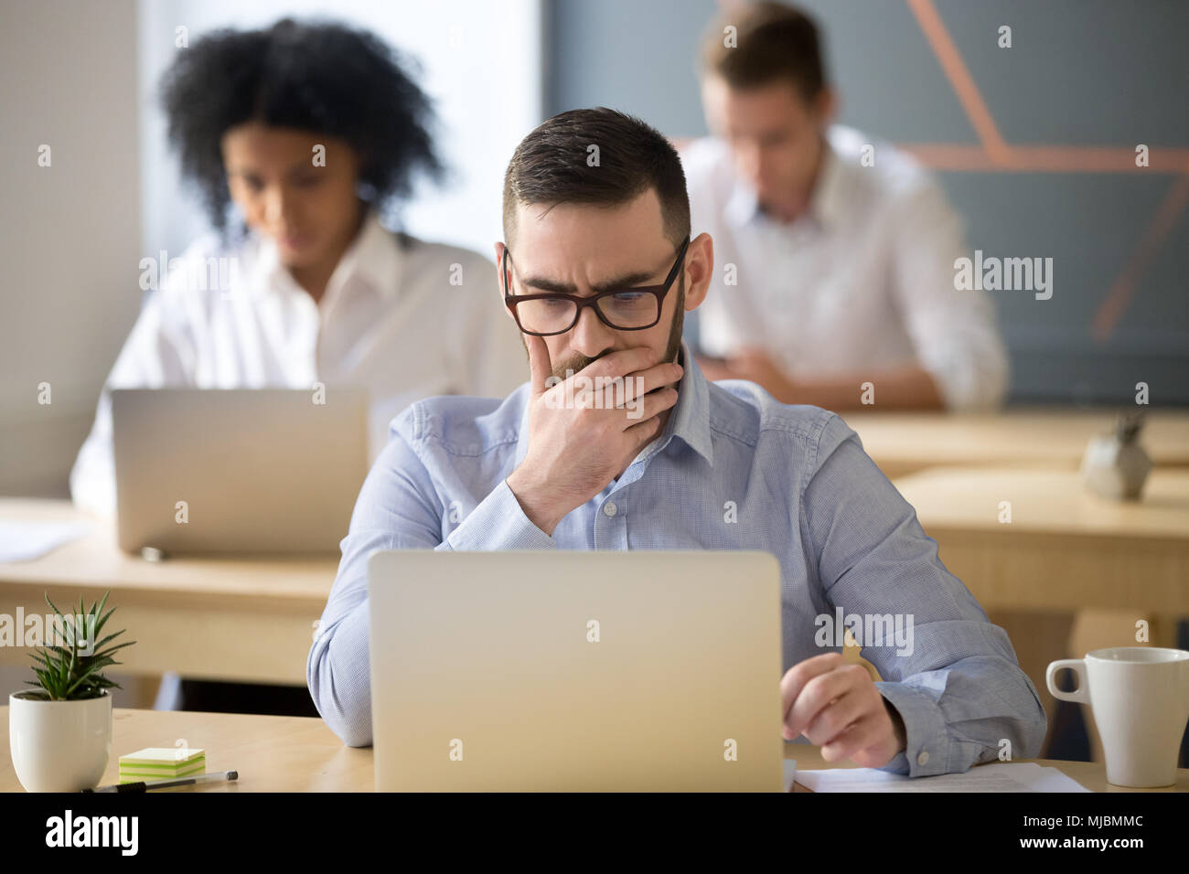 Focused businessman solving online problem working on laptop in  Stock Photo