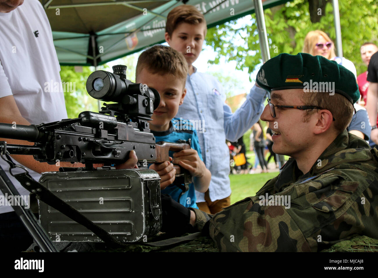 Polish Pvt. Lukas Wons, an infantryman with the 15th Mechanized Brigade, shows a Polish child a UKM-2000 machine gun during a bridge opening ceremony in Giżycko, Poland, May 1, 2018. The ceremony was held between the town of Giżycko and the Soldiers of Battle Group Poland: a unique, multinational coalition of U.S., U.K., Croatian and Romanian soldiers who serve with the Polish 15th Mechanized Brigade as a deterrence force in support of NATO’s Enhanced Forward Presence. (U.S. Army photo by Spc. Hubert D. Delany III /22nd Mobile Public Affairs Detachment) Stock Photo
