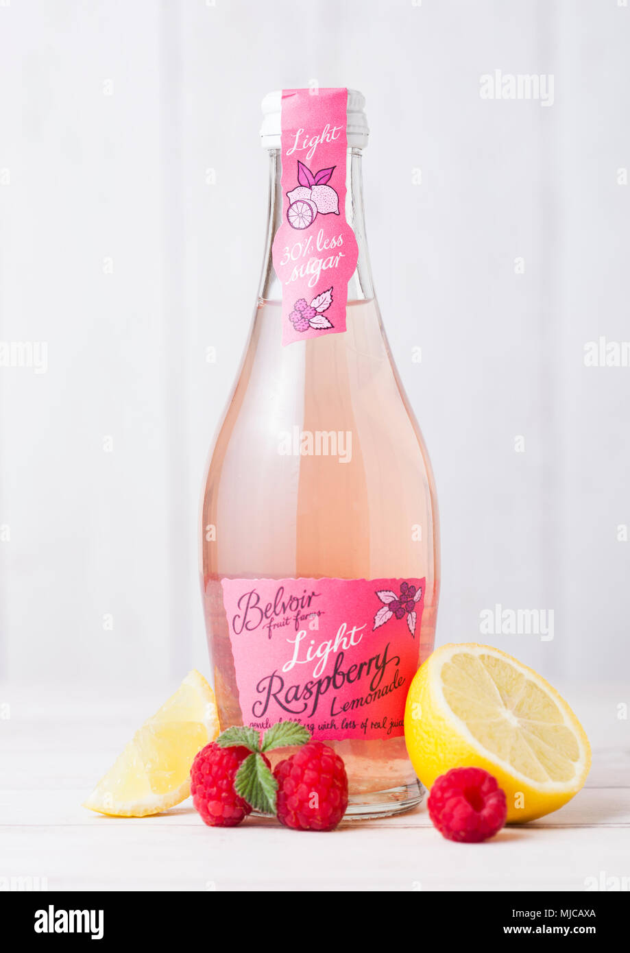 LONDON, UK - APRIL 27, 2018: Glass bottle of Belvoir soda drink lemonade with raspberry on wooden background with raw fruits and lemon. Stock Photo