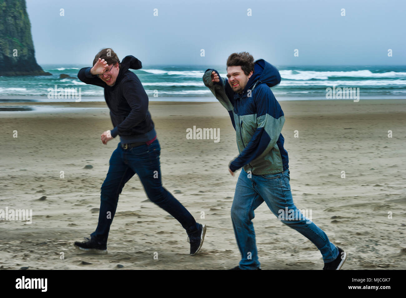 Two brothers brave the windy cold wet weather at Cannon Beach on the Oregon Coast Stock Photo