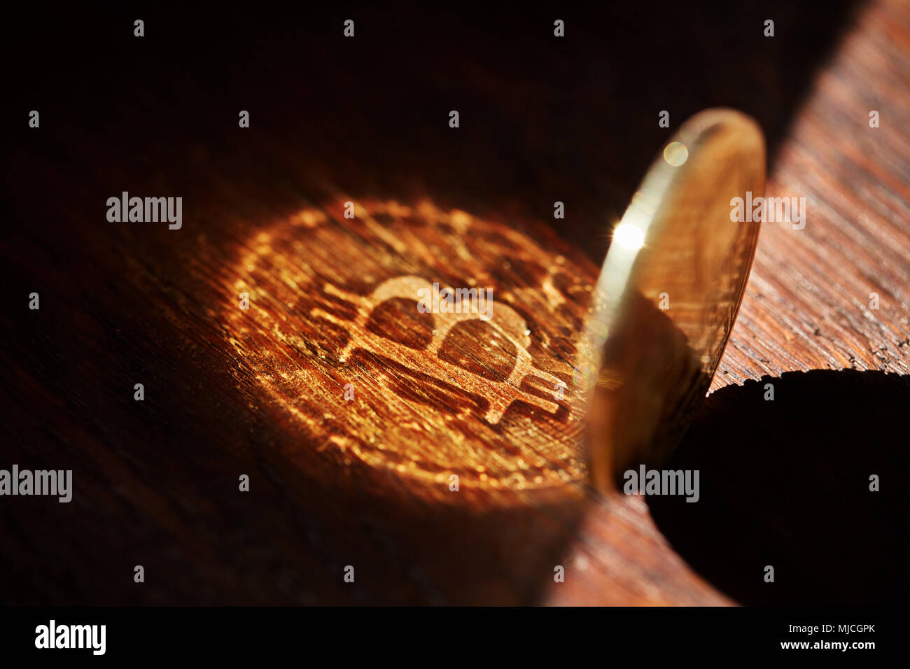 Bitcoin cryptocurrency with its shadow on wooden table, close-up, macro, selective focus, shallow depth of field. Some copy space for your inscription Stock Photo