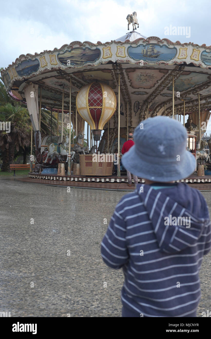 Boy before in front of an old carousel Stock Photo