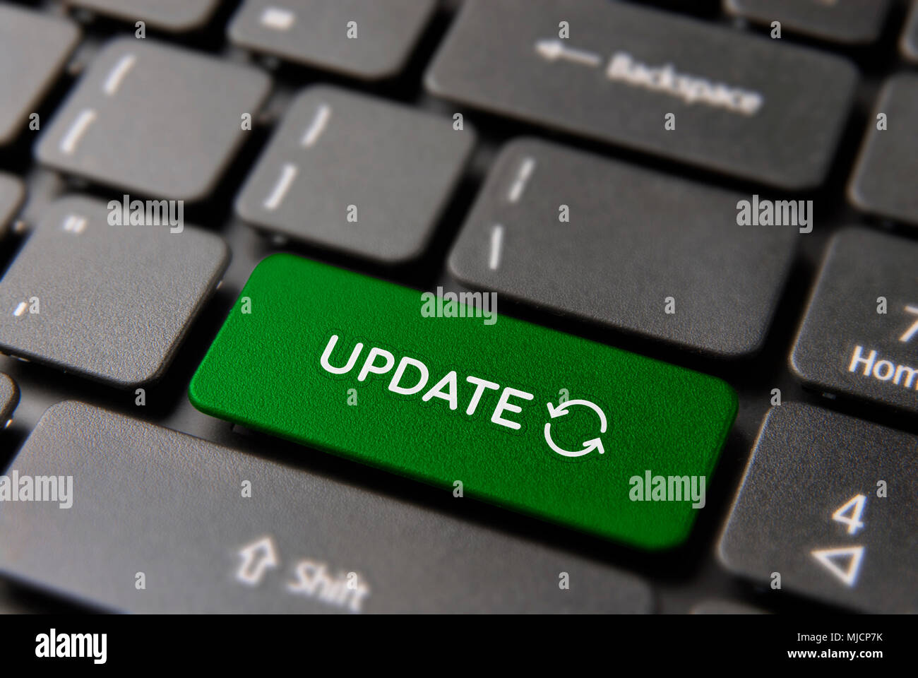 Online computer update concept: green key button with updating process symbol on laptop keyboard. Stock Photo