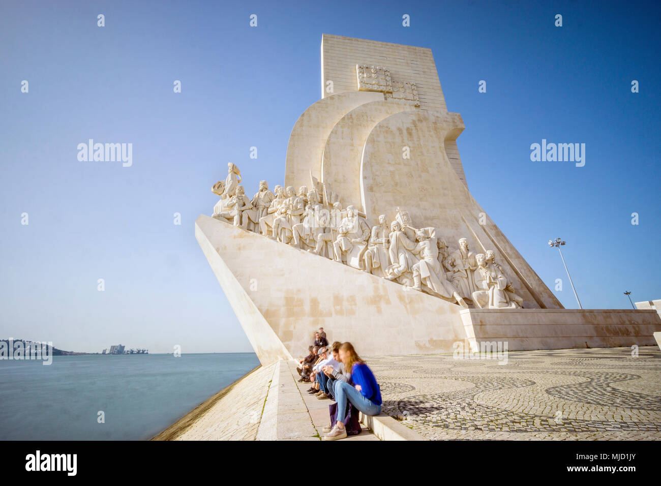 Tourists sitting next to Monument of the Discoveries in Belem, Lisbon, Portugal Stock Photo