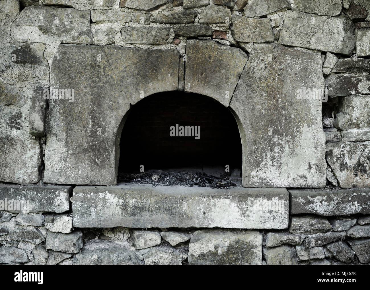 Fireplace in a wall from natural stone, charcoal remains, black, burnt Stock Photo