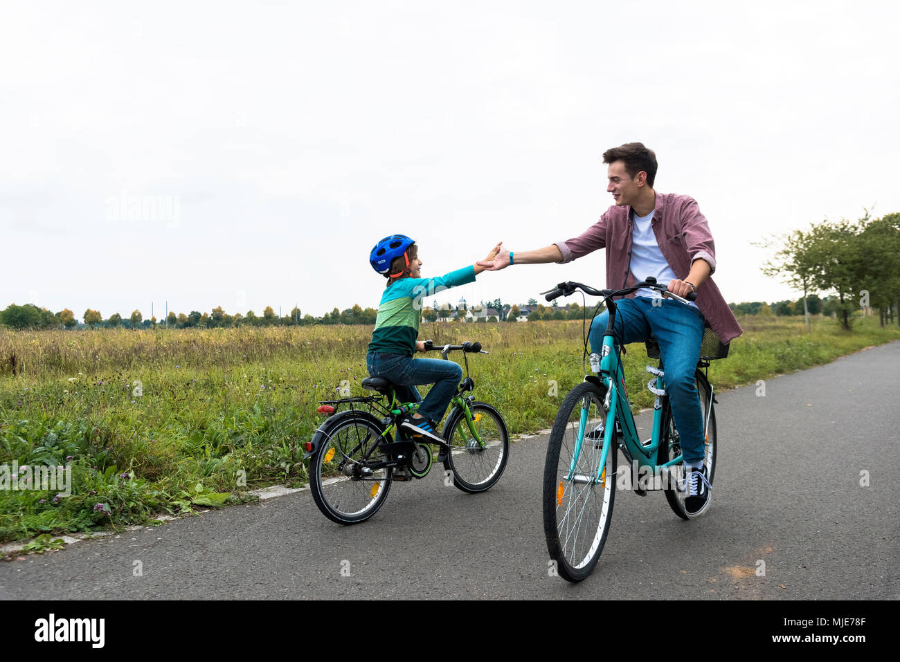 Boy while cycling, adult meets him, hands, touch, clap Stock Photo