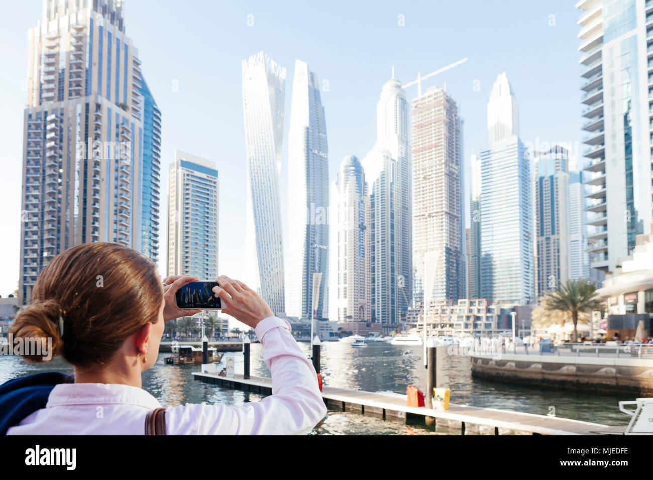 Dubai skyscrapers with Dubai Marina, female tourist taking a picture Stock Photo