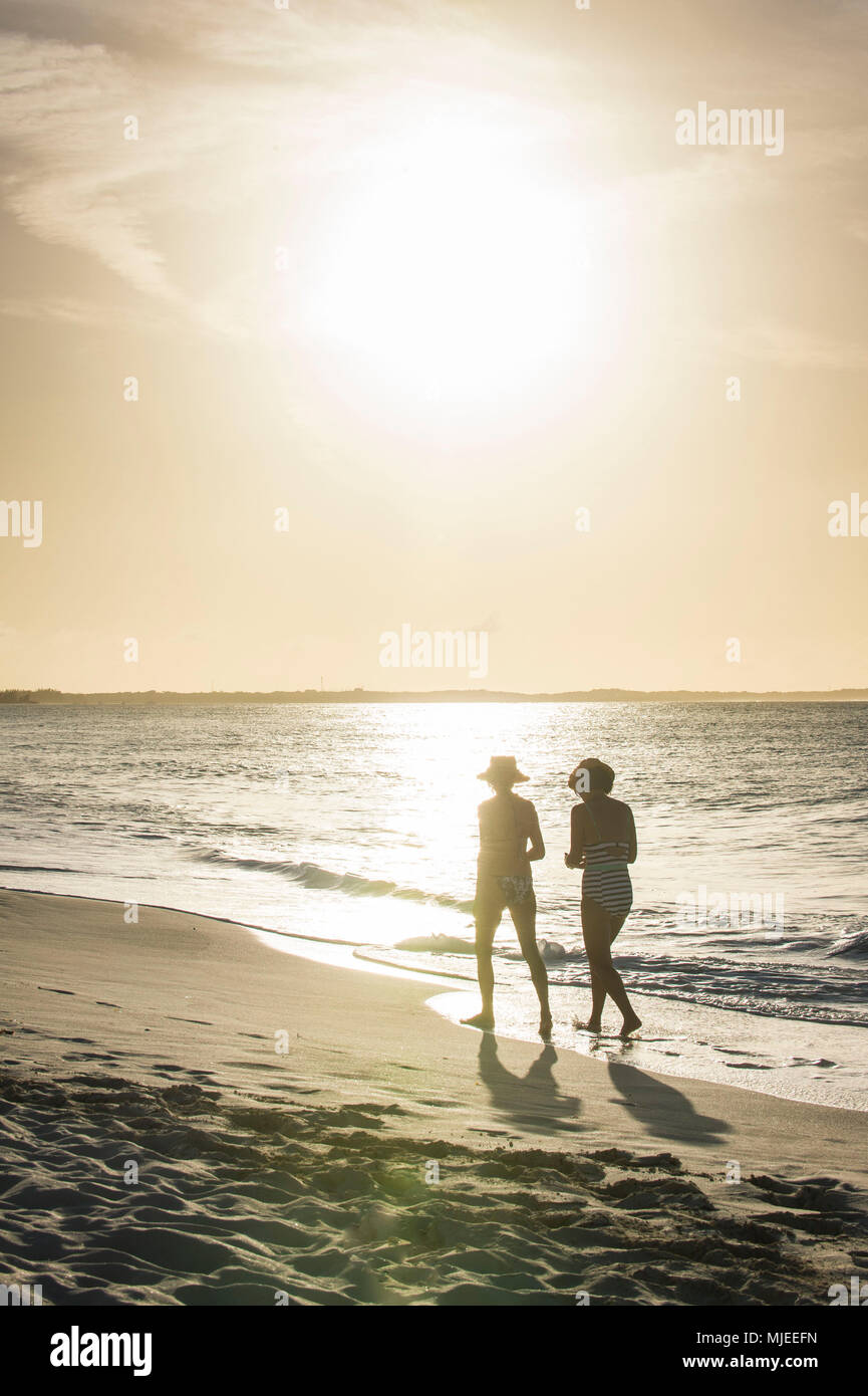 Two women walking on Grace bay beach at sunset, Providenciales, Turks and Caicos Stock Photo