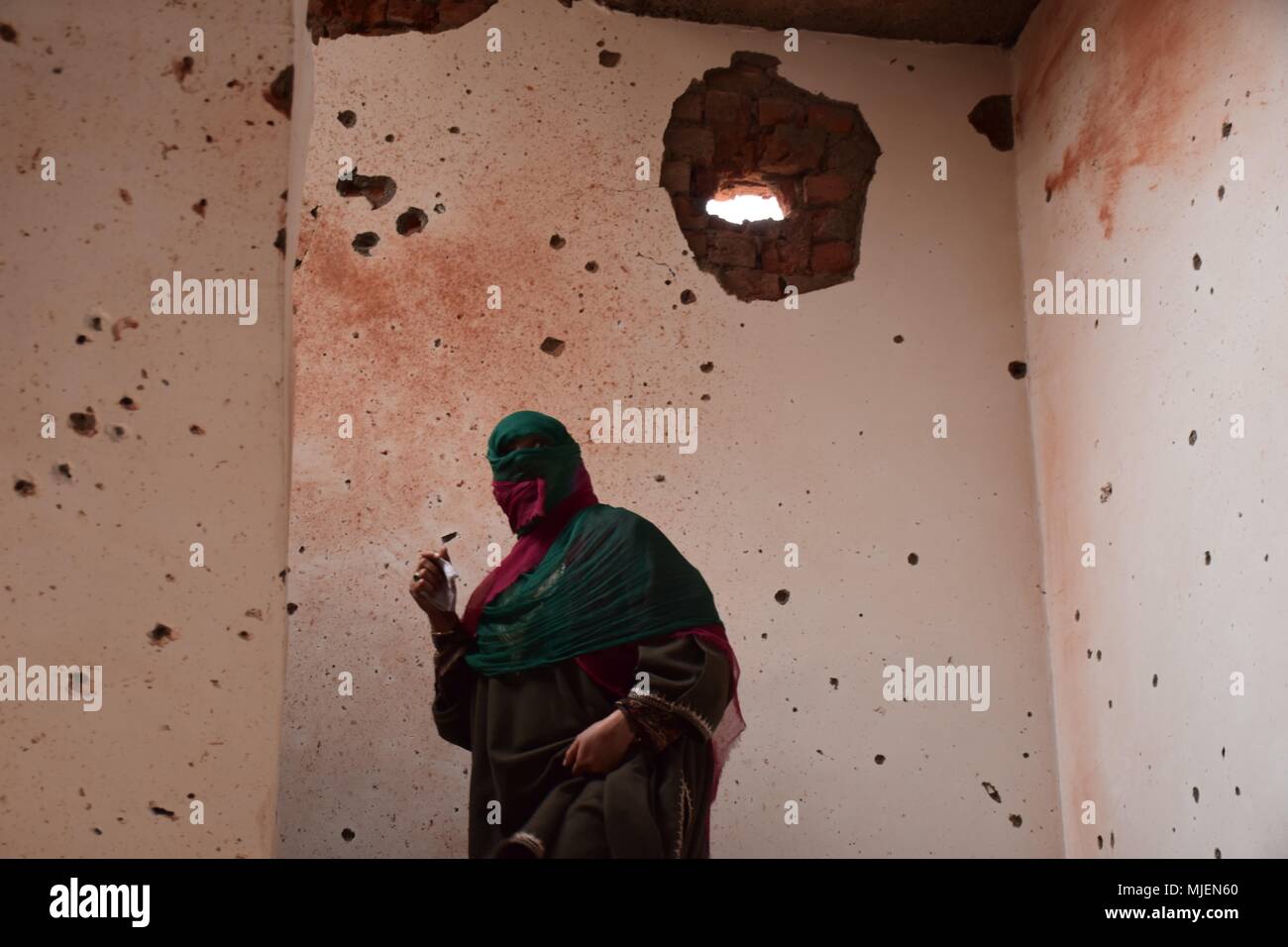 May 5, 2018 - Srinagar, Jammu & Kashmir, India - Women walks inside the partly damaged building in an encounter in Srinagar.4 Killed and several injured in an encounter between Indian forces and militants at chatabal area of Srinagar summer capital of Indian Kashmir on Saturday. Three militants were killed during a brief shootout after government forces laid seige around densely populated chatabal area of Srinagar. A young man also died after he was hit by the armoured vehicle during the clashes between the residents and police force as residents tried to help the Militants in escape. (Credit Stock Photo