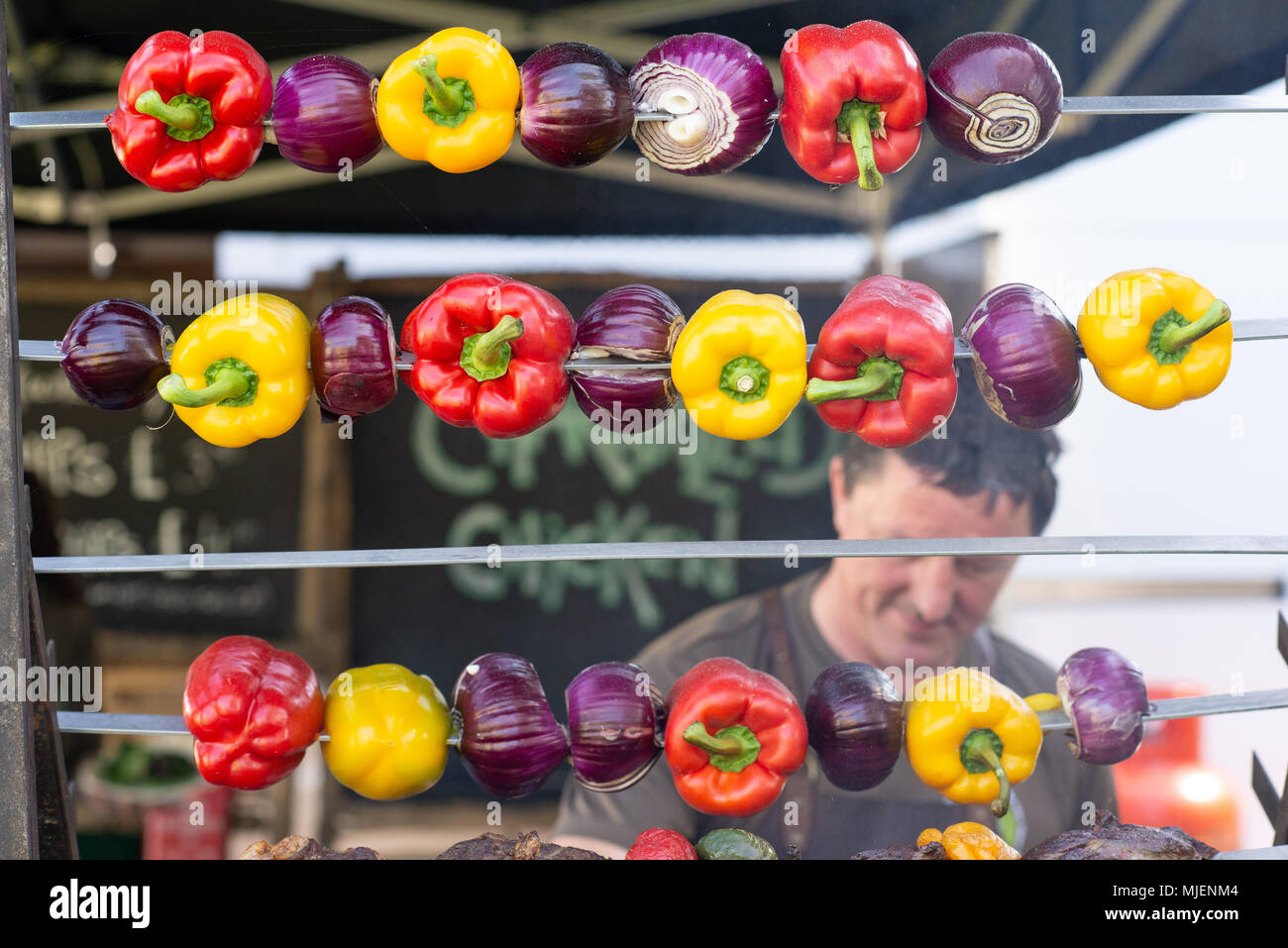 Sweet peppers roasting on a spit. The Borough, Downton, Salisbury, Wiltshire, UK, 5th May 2018. Mayday bank holiday weekend street fair celebrates the arrival of spring. Stock Photo